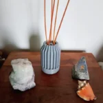 Difusor de aromas color gris con diseño acanalado impreso en 3D con varillas de madera sobre fondo blanco.